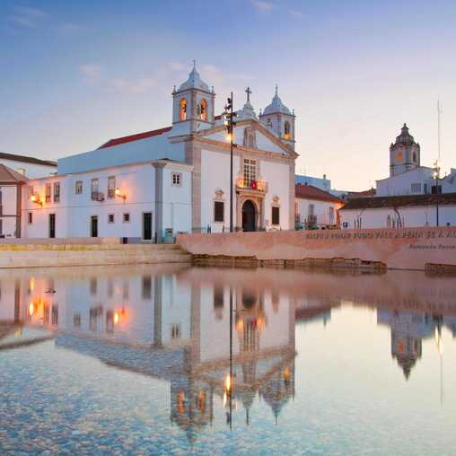 Historische Kirche in Lagos spiegelt sich im Wasser – charmante Altstadt mit Seefahrtsgeschichte an der Algarve.