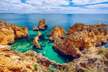 Felsige Bucht mit Boot in seichtem Wasser in Ponte da Piedade bei Algarve Lagos