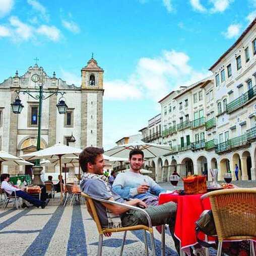 Menschen sitzen in einem Café in der Altstadt von Evora, einer Stadt, die zu den Sehenswürdigkeiten Portugals gehört.