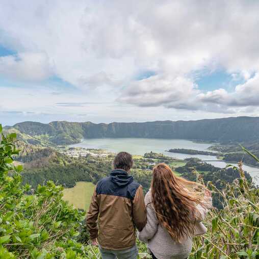 Wanderer genießen den Ausblick über die Vulkanlandschaft der Azoren auf São Miguel – sicherer Aktivurlaub in Portugal.