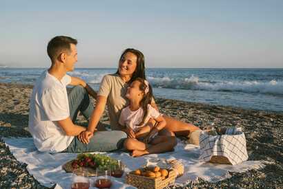Nordeste – Familien genießen entspannten Picknick-Moment am Meer bei Sonnenuntergang.
