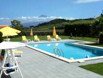 Pool mit gelben Sonnenliegen und Blick auf den Pico in der Quinta da Vista do Vale auf den Azoren