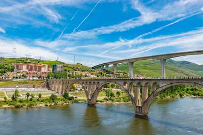 Moderne Häuser und Brücken am idyllischen Flussufer des Douro mit Doppelbrücke.