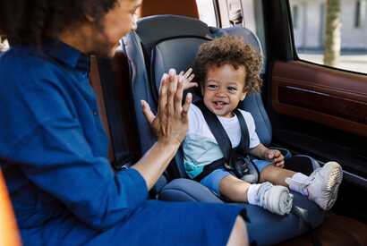 Eine Mutter fährt mit ihrem Kleinkind im Kindersitz – sicheres Reisen auf den Kapverden.