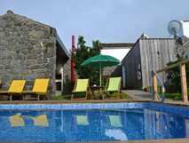 Pool mit bunten Liegestühlen und Natursteinfassade bei Tradicampo Casa do Tanque – ideal für entspannte Urlaubstage auf São Miguel.