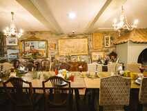 Großes Speisezimmer mit langen Holztischen, antiken Stühlen und Kunstwerken an den Wänden