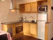 Apartaments Kosmos auf der Insel Faial, gemütliche Küche mit Holzschränken, Herd, Ofen, Kühlschrank, Mikrowelle, Wasserkocher und Kaffeemaschine.