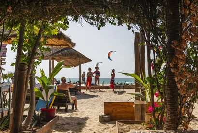 Strandbar mit Palmenblick auf das Meer und Kitesurfer am Horizont auf den Kapverden.