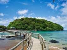 Bom Bom Resort auf Principe, idyllischer Holzsteg über kristallklares Wasser zum Restaurant der Anlage – perfekter Ort für Erholung und Naturerlebnis.