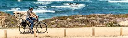 Eine Radfahrerin auf dem Weg entlang der Ecovia do Litoral mit dem Blick aufs Meer gerichtet