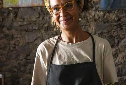 Lächelnde Kellnerin serviert ein traditionelles kapverdisches Gericht in einem lokalen Restaurant.