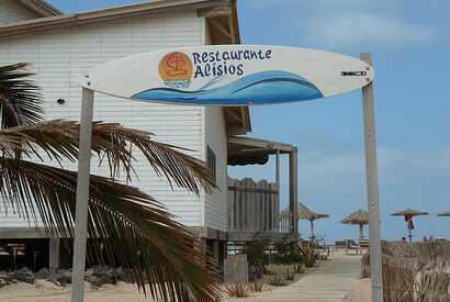 Restaurant mit Surfbrett-Schild am Strand auf den Kapverden – Treffpunkt für Surfer und Sonnenhungrige.