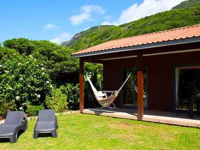 Bungalow mit Veranda, Hängematte und Sonnenliegen im Sitio da Assumada, eingebettet in grüne Hügel.