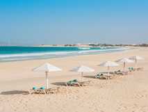 Voi Praia de Chaves Resort – Traumhafter, weißer Sandstrand mit türkisblauem Meer und gemütlichen Liegen unter Sonnenschirmen.