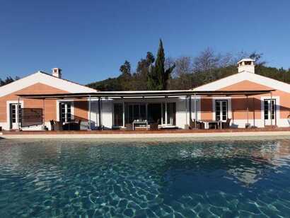 Blick auf den Pool und die Rückseite einer mit Naturmaterialien erbauten Unterkunft im Alentejo.