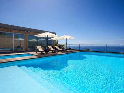 Pool des Aparthotel Mosteiros Place mit Sonnenliegen, Sonnenschirmen und traumhaftem Meerblick auf São Miguel