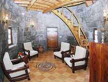 Moinho de Pedra auf Graciosa, gemütliches Wohnzimmer mit Steinambiente und elegantem Holztreppenaufgang in restaurierter Windmühle.