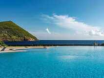 Infinity-Pool mit Meerblick vor grünem Hügel – Luxus und Erholung pur bei picotours.