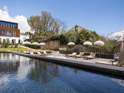 Senhora da Rosa Tradition & Nature Hotel auf Sao Miguel, luxuriöser Poolbereich mit stilvollen Liegen und schattigen Sonnenschirmen in idyllischer Naturkulisse – perfekter Ort zum Entspannen bei picotours.