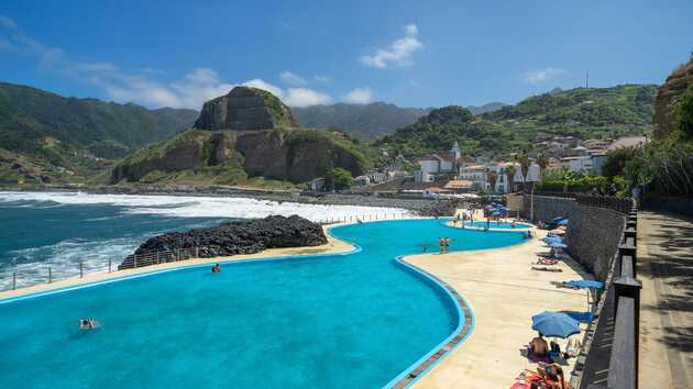 Blick von oben auf den Pool und das Meer, sowie die Berge in der Bucht.