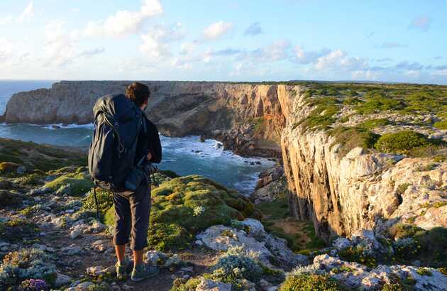 Wanderin mit Blick auf die Bucht, welche an der Westküste Portugals von hohen Klippen umrahmt wird.