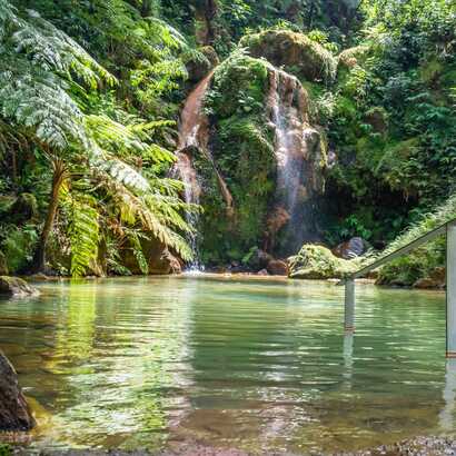 Idyllische Naturoase mit klarem Wasserfallbecken, ideal zum Entspannen und Erholen.