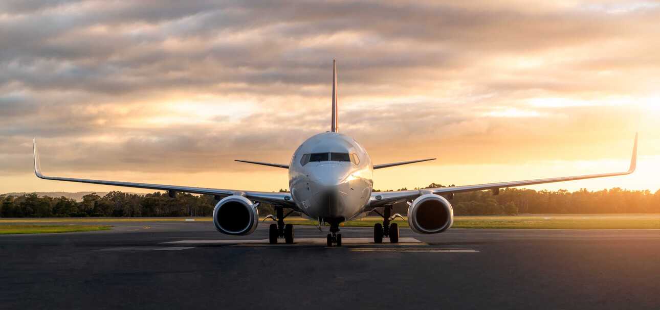 Ein Passagierflugzeug steht bei Sonnenaufgang startbereit auf der Landebahn – Symbol für Flugverbindungen auf die Kapverden.