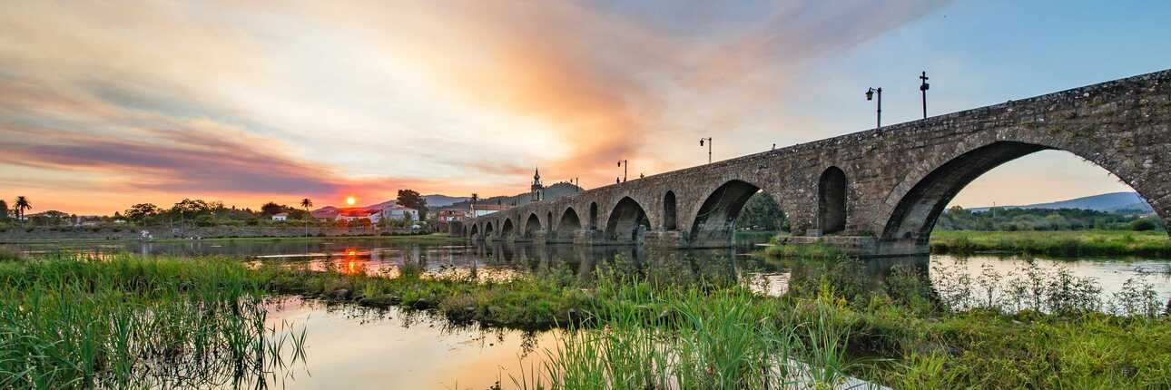 Ein stilles Gewässer, bewachsen mit historischer Brücke und Städtchen in der untergehenden Sonne - Ponte de Lima