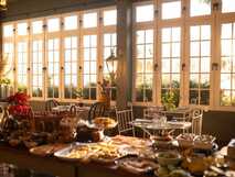 Lichtdurchfluteter Frühstücksraum mit reichhaltigem Buffet und Blick in den Garten