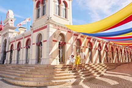 Familie posiert im Schatten bunter Tücher, die von der Burg in Loule über dem Platz davor gespannt sind.