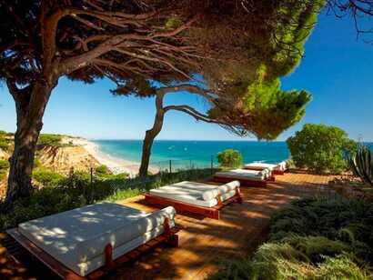 Eine Terrasse des Hotels am Strand der Algarve, gesäumt von Pinien und sanften Dünen.