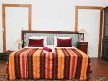 Casa Colonial König auf Fogo, gemütliches Schlafzimmer mit farbenfroher Bettdecke und traditionellem Ambiente für erholsame Nächte.