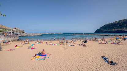 Badegäste am goldgelben Sandstrand Praia da Banda d’Além in Machico auf Madeira
