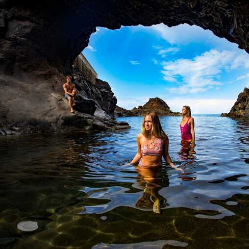 Drei Menschen schwimmen in einem natürlichen Vulkanbecken auf Madeira und genießen den Atlantik.