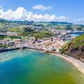 Bucht von Porto Pim auf Faial mit geschütztem Sandstrand, türkisblauem Wasser und Blick auf die Küstenstadt Horta auf den Azoren