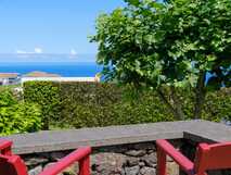 Tradicampo - Casa da Fonte auf Sao Miguel, Terrasse mit rotem Sitzmobiliar und entspannendem Blick auf das blaue Meer und die grüne Landschaft.