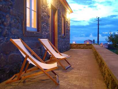 Zwei Liegestühle auf der Terrasse eines Natursteinhauses mit Blick auf den Abendhimmel – Casa da Fonte auf São Miguel.