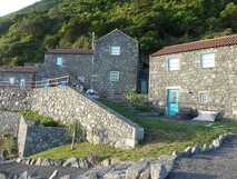 Traditionelles Landhaus Abrigo da Cascata auf Pico mit Natursteinfassade, blauen Fensterläden und grüner Hanglage