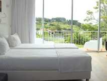 ANC Experience Resort auf Sao Miguel, modernes und helles Schlafzimmer mit Blick auf grüne Landschaft und privatem Balkon – ideal für entspannte Urlaubsmomente.