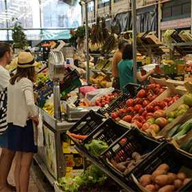 Personen stehen vor einem Obststand in einer Markthalle in RIbeira