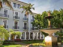 Azoris Angra Garden Hotel mit klassischer Fassade, Palmen und historischem Brunnen im gepflegten Garten von Angra do Heroísmo
