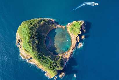 Luftaufnahme der Ilhéu de Vila Franca do Campo mit kreisrunder Lagune und Boot beim Verlassen der Insel