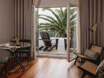 Casa Portuguesa Boutique Hotel auf Sao Miguel, stilvolles Zimmer mit Balkon und Blick auf tropische Palmen – perfekter Rückzugsort für entspannte Tage bei PicoTours.