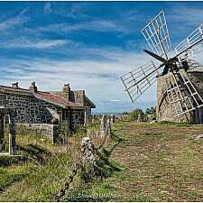 Alte Stein-Windmühle und traditionelles Granithaus auf einer Anhöhe in Nordportugal.