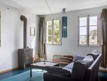Estrela do Atlantico auf Faial – heller Wohnraum mit Kamin, gemütlichem Sofa und großen Fenstern, die Tageslicht und Ausblick auf grüne Umgebung bieten.