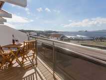 Balkon mit Holzmöbeln und Wein vor traumhaftem Meerblick – Ihr entspannter Urlaub mit picotours.