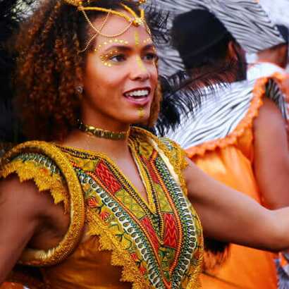 Tänzerin in goldfarbenem Kostüm beim Karneval auf Kap Verde, umgeben von feiernden Menschen in bunten Outfits.