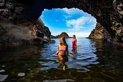 Drei Menschen schwimmen in einem natürlichen Vulkanbecken auf Madeira und genießen den Atlantik.