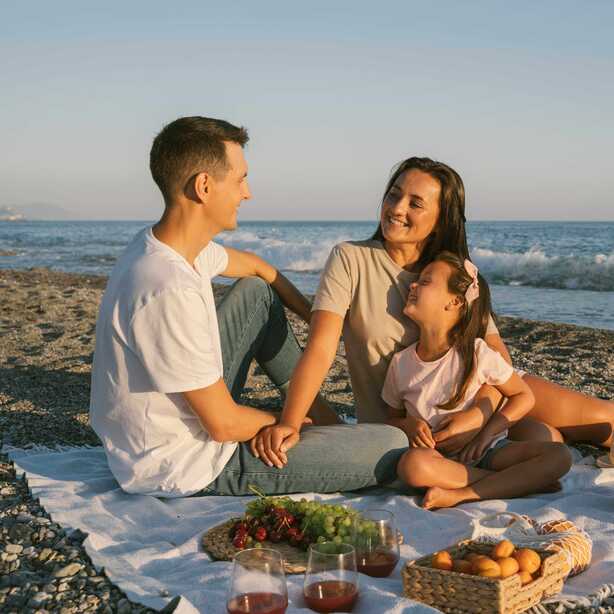 Nordeste – Familien genießen entspannten Picknick-Moment am Meer bei Sonnenuntergang.