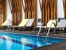 Innenpool im Ponta Delgada Hotel mit gelben Liegen und stilvoller Holzstruktur an der Wand
